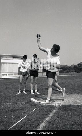 1989, historisch, Schulsporttag, ein männlicher Sportlehrer in der Sekundarschule, der den Schülern den Schuss gezeigt hat, ein Ereignis, bei dem ein schwerer Kugelball, der so weit wie möglich von einem kleinen Kreis aus bekannt ist, in England, Großbritannien, geworfen wurde Stockfoto