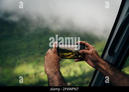 Eine Person, die mit einem Mobiltelefon eine Landschaft mit einem unscharfen Hintergrund fotografiert. Hochwertiges Foto Stockfoto