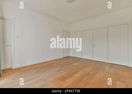 Ein leeres Zimmer mit Holzfußboden und weißen Türen auf beiden Seiten des Zimmers, es hängt ein blauer Vorhang von der Decke Stockfoto