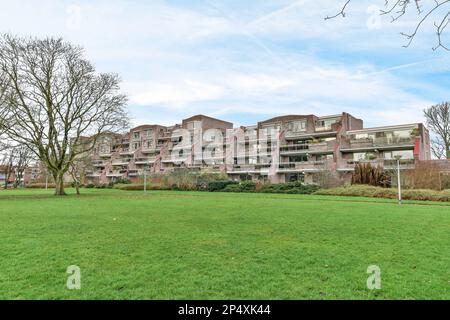 Ein Apartmentkomplex mit grünem Gras und Bäumen im Vordergrund auf einem hellen, blauen Himmel Stock Foto Stockfoto