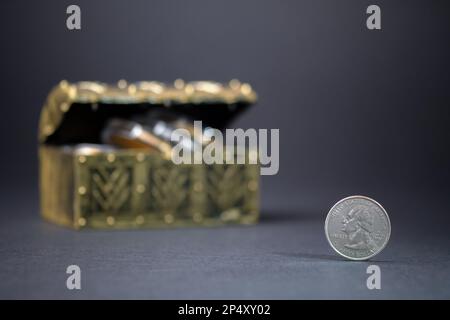 Eine Vierteldollar-Münze auf dunklem Hintergrund. Sparen und investieren Sie Geld für die Zukunft. Eine Dollar-Schatzkiste Stockfoto
