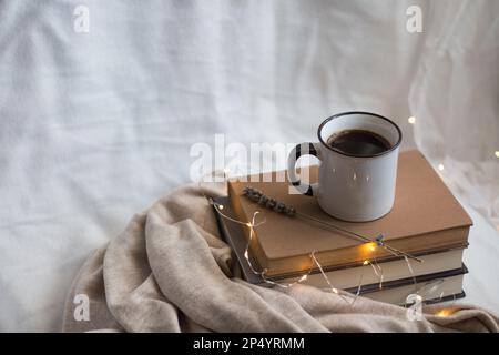 Gemütliche Inneneinrichtung mit einer Tasse Kaffee, Büchern und Lavendel für ideale Entspannung zu Hause. Stockfoto