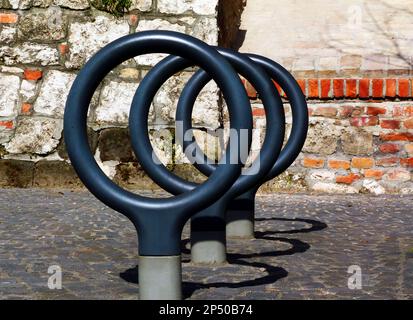 Ringförmige Fahrradträger aus Stahl, gegossen in Pflastersteinpflaster. Weicher, alter Stein- und Ziegelhintergrund. Schwindende Perspektive. Speicherplatz kopieren Stockfoto