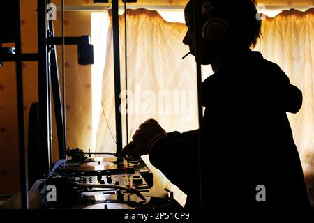 Männlicher DJ, der morgens bei einer Party Platten auf den Decks spielt. Stockfoto