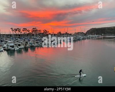 Dana Point, Kalifornien, USA. 7. Januar 2023. Im Hafen von Dana Point in Orange County, Südkalifornien, leuchtet ein feuriger roter Sonnenuntergang über einem Stand-Up-Paddle-Board SUP-Fahrer. (Kreditbild: © Ruaridh Stewart/ZUMA Press Wire) NUR REDAKTIONELLE VERWENDUNG! Nicht für den kommerziellen GEBRAUCH! Stockfoto