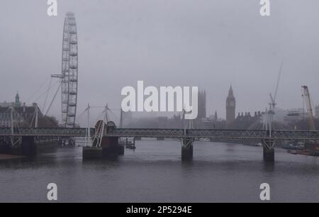 London, Großbritannien. 25. Januar 2023 Ein Blick auf das London Eye, die Houses of Parliament, die Hungerford und Golden Jubilee Bridges sowie die Themse, während die Hauptstadt von eiskaltem Nebel bedeckt wird. Stockfoto