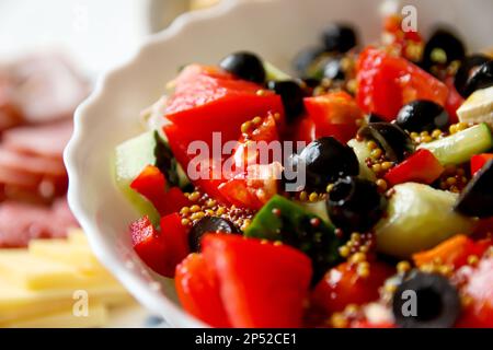 Salatschüssel. Nahaufnahme Sommersalat. Klassischer griechischer Salat aus Tomaten, Gurken, rotem Pfeffer, Zwiebeln mit Oliven, Oregano und Fetakäse. Frisch gemischt Stockfoto