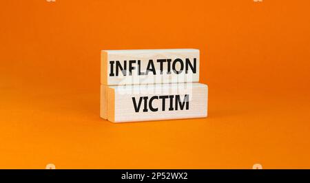 Symbol für Inflationsopfer. Konzeptwörter Inflationsopfer auf Holzblock. Schöner orangefarbener Tischhintergrund. Das Konzept der Inflationsopfer von Unternehmen. Stockfoto