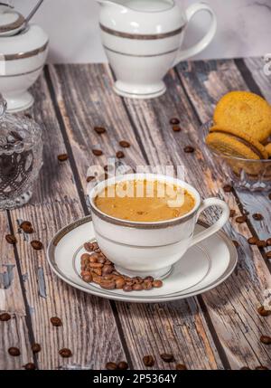 Kaffeetasse, Kaffeebohnen und Süßigkeiten im Hintergrund Stockfoto