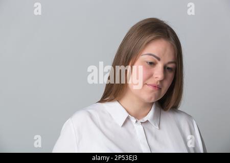 Studioporträt einer unglücklichen, übergewichtigen Frau. Junge Erwachsene ukrainische Frau, die frustriert nach unten schaut Stockfoto