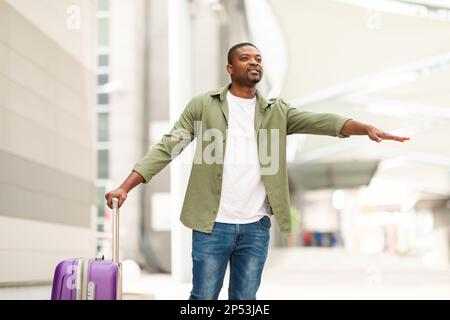 Afrikanischer Männlicher Tourist Hailing Taxi Mit Geste Steht In Der Nähe Des Flughafens Stockfoto