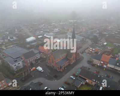 Rijkevorsel, Belgien, 23. Februar 2023, kleines Dorf Sint Jozef, auf dem Kanal Dessel Schoten Luftfoto während des Morgennebels in Rijkevorsel, kempen, Belgien, mit den Häusern und Straßen des Dorfes um die Kirche in der natürlichen grünen landwirtschaftlichen Landschaft. Hochwertiges Foto. Hochwertiges Foto Stockfoto
