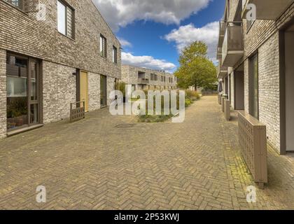 Moderne Wohngemeinde in der niederländischen Stadt Groningen. Zeitgenössische Apartments im flachen Wohngebäude von außen. Gehäusestruktur mit Comm Stockfoto