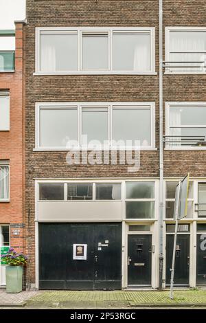 Amsterdam, Niederlande - 10. April 2021: Ein Backsteingebäude mit zwei Garagen vorne und einer auf der anderen Seite ist eine leere Straße Stockfoto