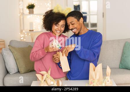 Glückliches schwarzes Paar, das zu Hause ostergeschenke vorbereitet Stockfoto