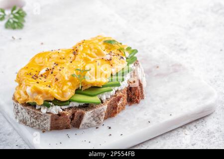 Rührei mit geräuchertem Lachs, Frischkäse und Avocado auf Toast Stockfoto