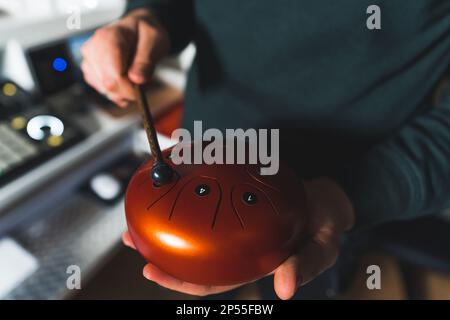 Nahaufnahme einer glücklichen Stahltrommel an der Hand eines Mannes, Musiksystem im Hintergrund. Hochwertiges Foto Stockfoto