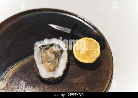 Eröffnete Auster mit Zitrone und Messer, Meeresfrüchte-Konzept. Hochwertiges Foto Stockfoto