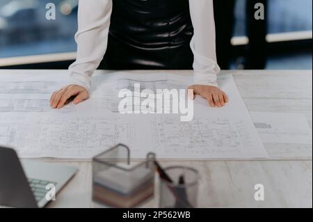 Die Designerin der Architektin hält ihre Hände auf dem Tisch und sieht sich das Projekt des Hauses an Stockfoto