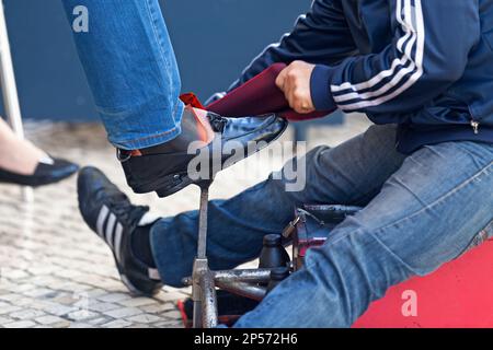 Lissabon, Portugal - Juni 02 2018: Schuhputzer auf der Arbeit in der Altstadt, wo es viele Touristen gibt. Stockfoto
