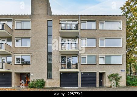 Ein Apartmentgebäude mit zwei Garagen vorne und drei Ballen in der Mitte im obersten Stockwerk Stockfoto