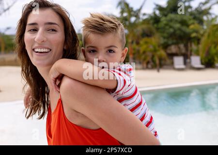 Porträt von glücklicher birassischer Mutter und Sohn, die sich am Swimmingpool umarmen Stockfoto