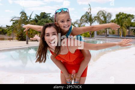 Porträt einer glücklichen, birassischen Mutter und Tochter, die am Pool spielen Stockfoto