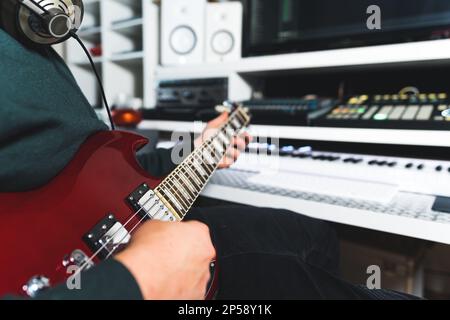 Unbekannter Musiker mit Kopfhörern, der die Bassgitarre in einem Heimkino spielt. Hochwertiges Foto Stockfoto