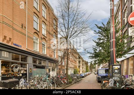 Einige Fahrräder parkten an einer Straßenseite vor einem Ziegelgebäude mit einem Stoppschild Stockfoto