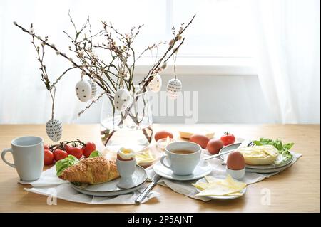 Frühstück mit Ostereierdekoration auf einem hölzernen Esstisch, Platz für Frühlingsferien, Kopierbereich, ausgewählter Fokus, schmale Feldtiefe Stockfoto