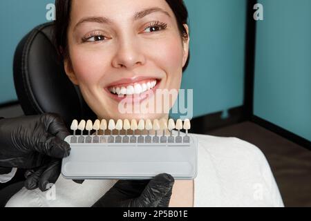 Lächeln und weiße Zähne einer jungen Frau. Anpassung der Schattierungen der Implantate oder des Zahnaufhellungsprozesses. Stockfoto