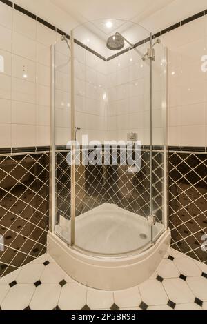 Ein Badezimmer mit schwarz-weißen Fliesen an den Wänden, Duschkabine und Toilette im Boden ist aus Marmor Stockfoto