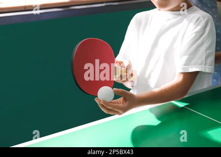 Kleiner Junge, der drinnen Tischtennis spielt, Nahaufnahme Stockfoto