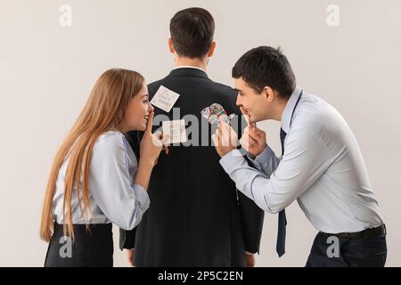Geschäftsleute, die ihren Kollegen vor hellem Hintergrund einen Streich spielen. Feier zum 1. April Stockfoto