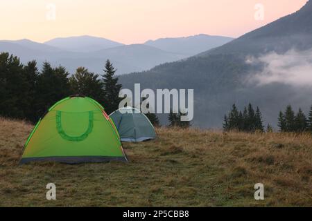 Malerischer Blick auf die Berglandschaft mit Nebel und Campingzelten am frühen Morgen Stockfoto