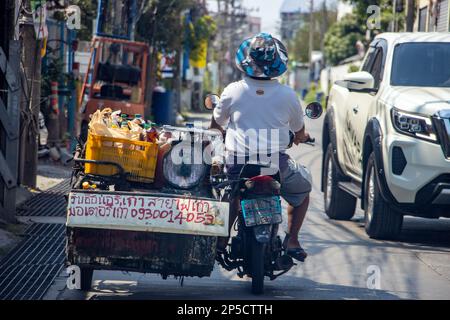 SAMUT PRAKAN, THAILAND, FEBRUAR 05 2022, Ein Mann transportiert Speiseöl auf einem Motorrad mit Beiwagen, der als Werbung für den Kauf von gebrauchten dient Stockfoto