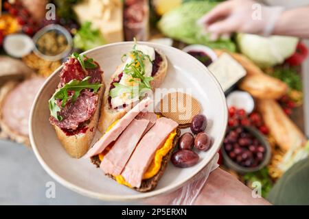 Der Kellner macht Bruschetta oder Tapas. Tisch voller mediterraner Vorspeisen, Tapas oder Antipasto. Auswahl an italienischen Speisen. Köstlicher Snack auf der Party Stockfoto
