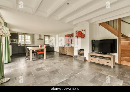 Amsterdam, Niederlande - 10. April 2021: Ein Wohnzimmer mit Treppe bis zur zweiten Etage und eine offene Küche auf der rechten Seite Stockfoto