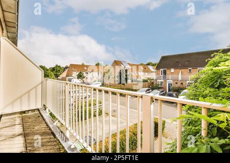 Ein Außenbereich mit Häusern im Hintergrund und grünen Pflanzen, die an der Seite des eingezäunten Hofes wachsen Stockfoto