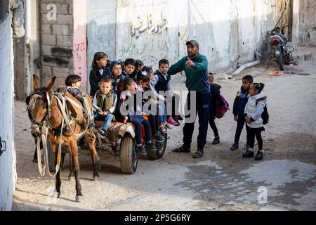 Gaza, Palästina. 06. März 2023. Louay Abu Sahloul transportiert Kinder zu einem Preis von 5 Schekel (1,4 US-Dollar) pro Monat in Khan Yunis im südlichen Gazastreifen in einen Kindergarten mit einem Eselwagen. Kredit: SOPA Images Limited/Alamy Live News Stockfoto