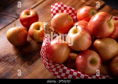 Mehrere königliche Gala-Äpfel (Malus domestica) auf einem rustikalen Holztisch. Apfelbäume werden weltweit angebaut und sind die am weitesten verbreitete Art des g. Stockfoto