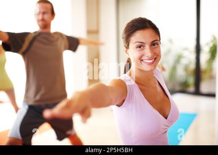 Ich liebe die Dehnübungen. Eine junge Frau, die Yoga-Stretch in einem Yoga-Kurs macht. Stockfoto