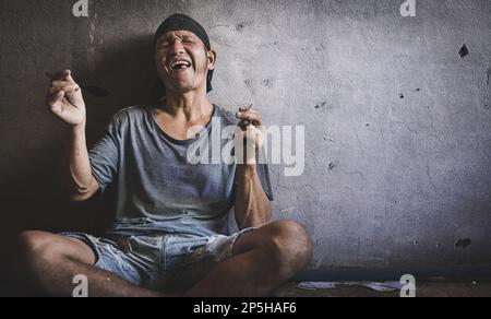 Das süchtig machende Konzept eines Mannes, der sitzt und seine Herointasche trägt. Selbstzerstörerische Depression, Drogenabhängigkeit, Selbstmord, Drogenabhängigkeit. Stockfoto