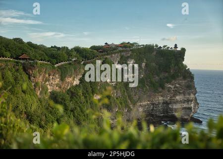 Panoramaaufnahme des spektakulären Tempelkomplexes Pura Luhur in Uluwau auf Bali entlang der majestätischen, grün bedeckten Klippen, die ins Meer fließen. Stockfoto