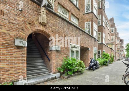 Amsterdam, Niederlande - 10. April 2021: Ein Backsteingebäude mit Treppen zur Haustür und Fahrrad auf dem Gehweg in amsterdam, niederlande Stockfoto