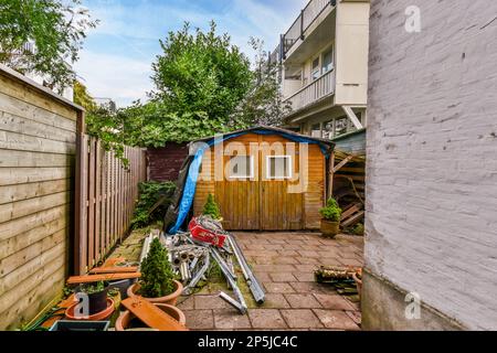 Ein Hinterhof mit vielen Dschunks auf dem Boden und Mülltonnen vor dem Haus daneben Stockfoto
