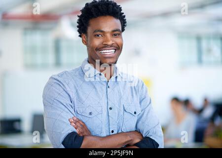 Er vertraut auf seine geschäftlichen Fähigkeiten. Porträt eines gutaussehenden jungen Geschäftsmanns, der mit gefalteten Armen im Büro steht. Stockfoto