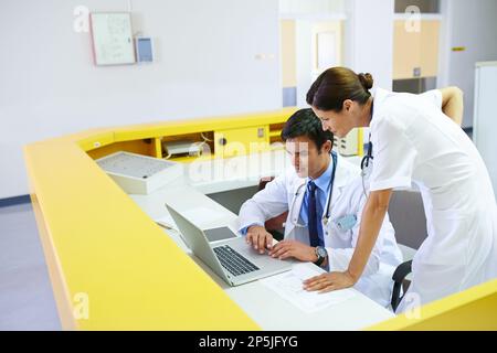 Das sieht nicht gut aus. Ein gutaussehender junger Arzt und seine Pflegehelferin mit einem Laptop. Stockfoto