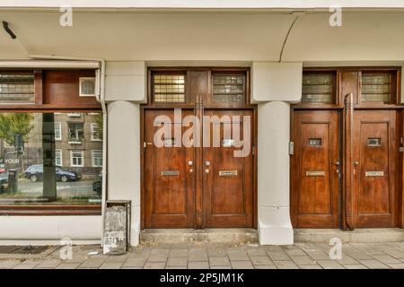 Zwei Holztüren vor einem Gebäude, das weiß gestrichen wurde und als Eingangsbereich dient Stockfoto