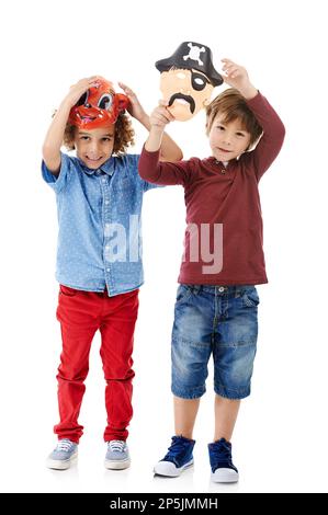Bereit zum Spielen. Studioaufnahme von zwei süßen kleinen Jungen, die Masken vor weißem Hintergrund tragen. Stockfoto